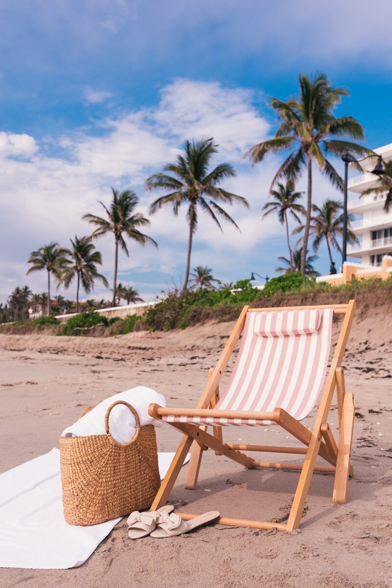 Striped beach chair with straw bag on Palm Beach sand