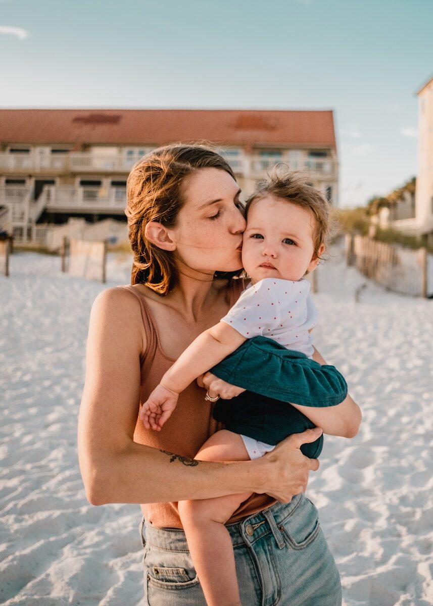Mother kissing baby at golden hour